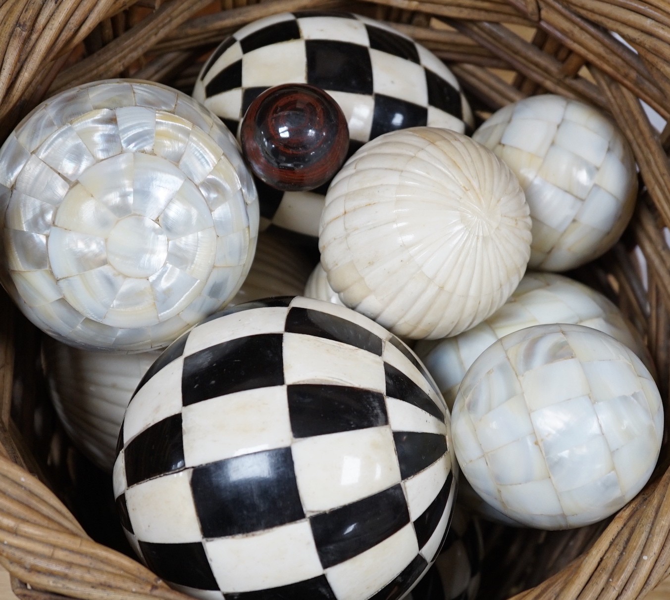 A basket of mother of pearl or bone veneered balls and other decorative balls